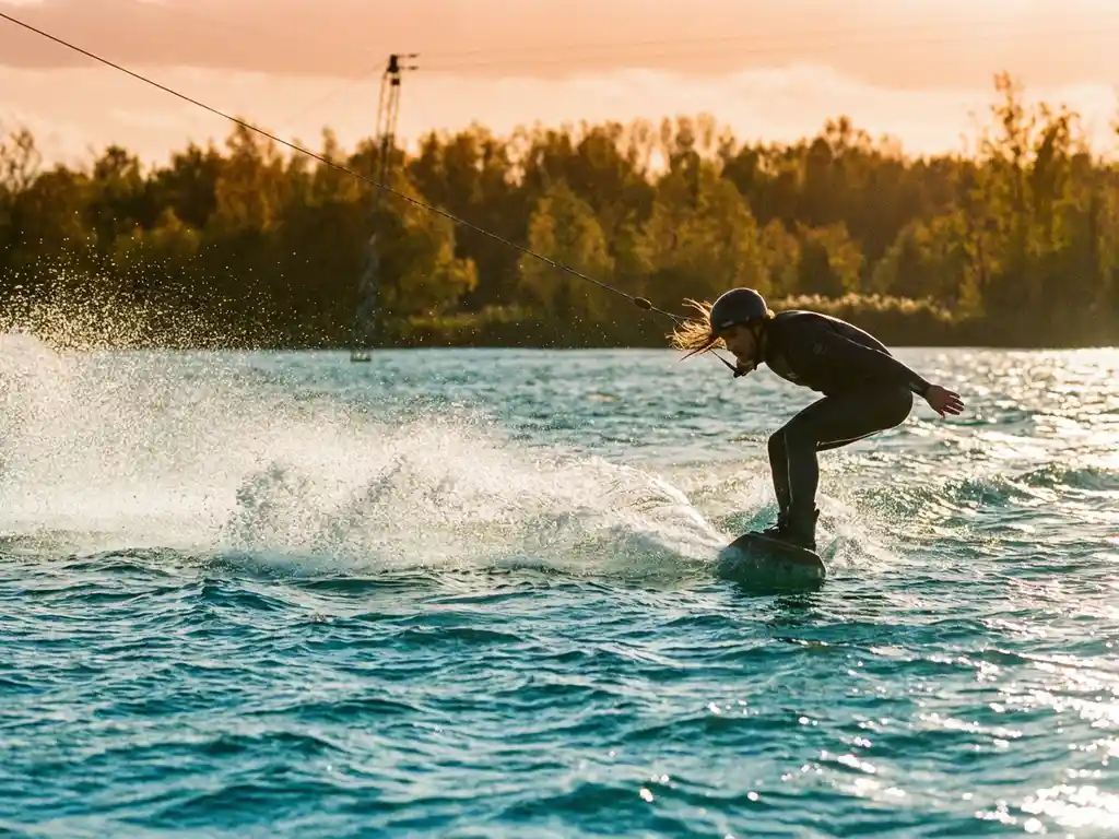 Wakeboarder snijdt door kabbelig water met opspattend schuim in gouden namiddaglicht